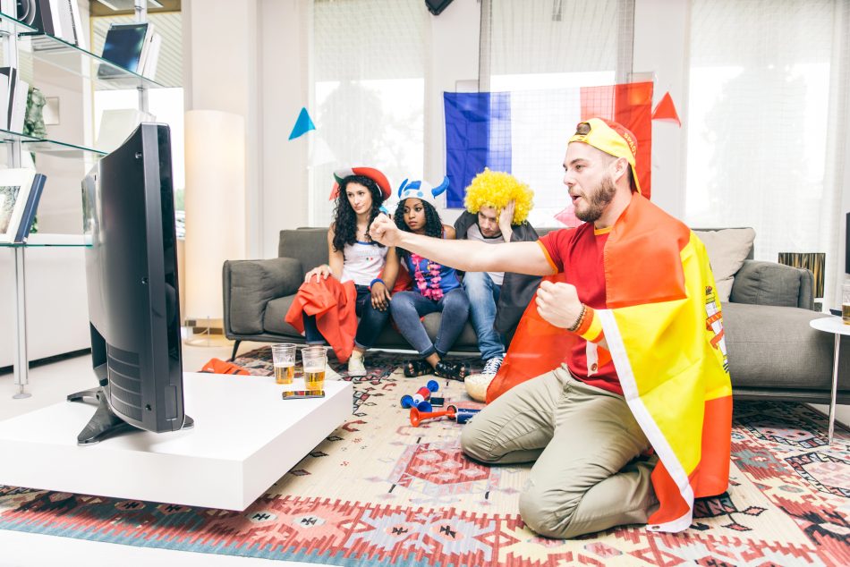 Football fans watching a match on television at home