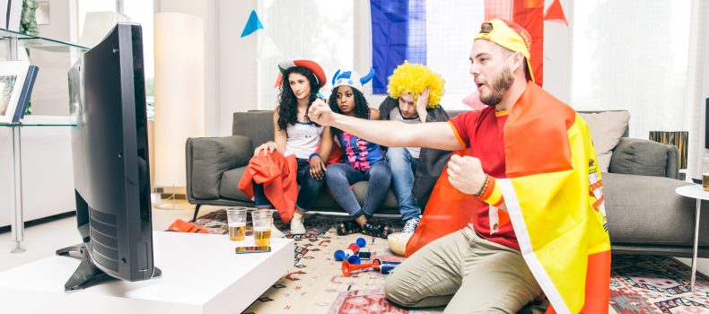 Football fans watching a match on television at home
