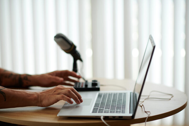 Podcaster editing a recorded episode on a laptop next to a microphone
