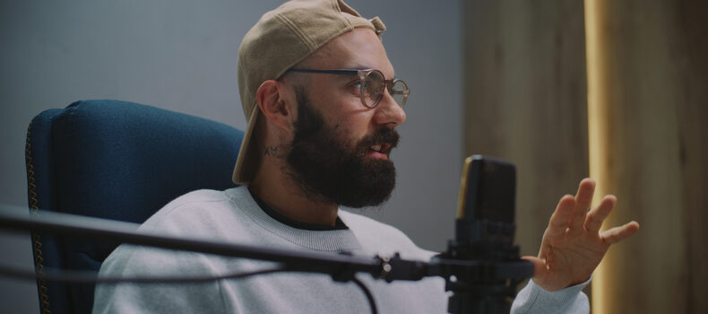 Podcast host speaking into a condenser microphone in a recording studio