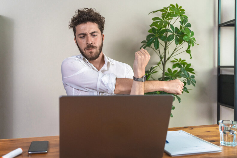 Man stretching his stiff shoulders at his desk before a recording session